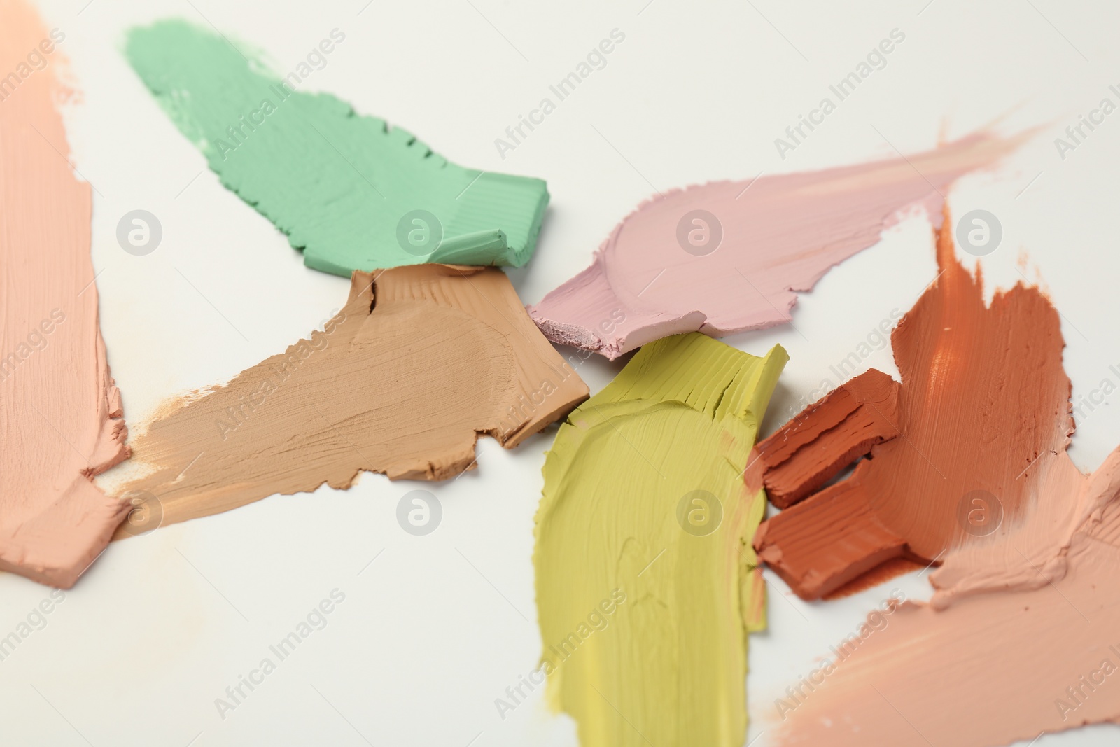 Photo of Samples of different color correcting concealers on white background, closeup