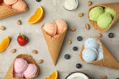 Photo of Flat lay composition with delicious ice creams in waffle cones on table