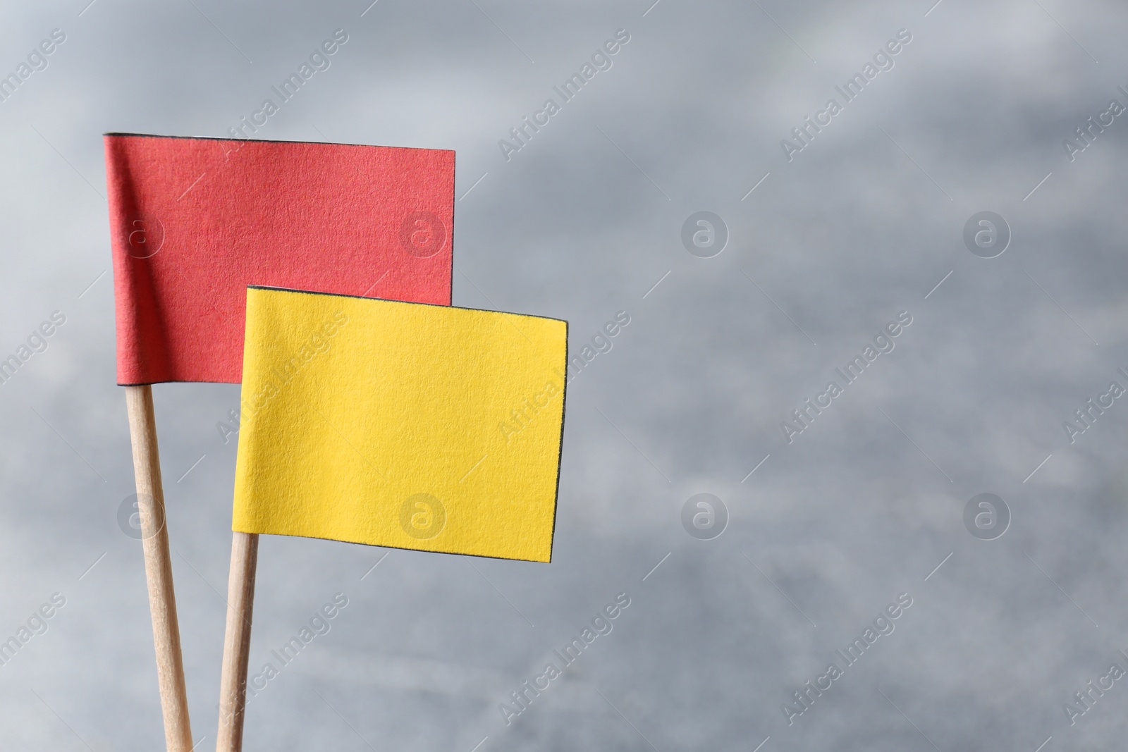 Photo of Small color paper flags on blurred background, closeup. Space for text