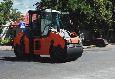 Image of Roller working on city street. Road repairing