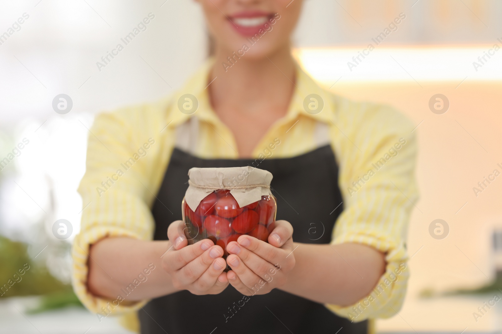 Photo of Woman holding jar of pickled vegetables in kitchen, closeup