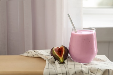 Photo of Delicious fig smoothie in glass on table indoors