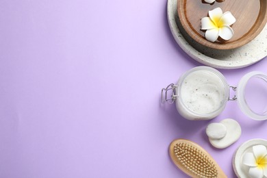 Flat lay composition with body scrub and plumeria flowers on violet background, space for text