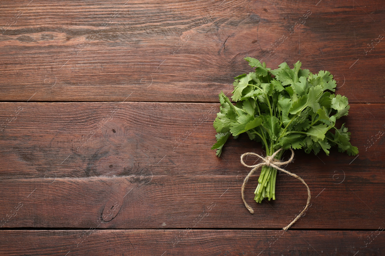 Photo of Bunch of fresh coriander on wooden table, top view. Space for text