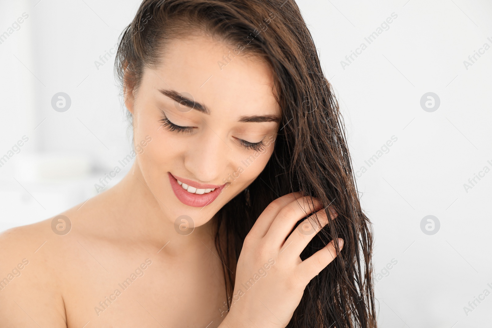 Photo of Beautiful young woman applying hair conditioner in bathroom