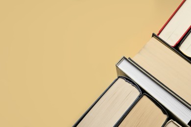 Photo of Many hardcover books on light yellow background, closeup. Space for text