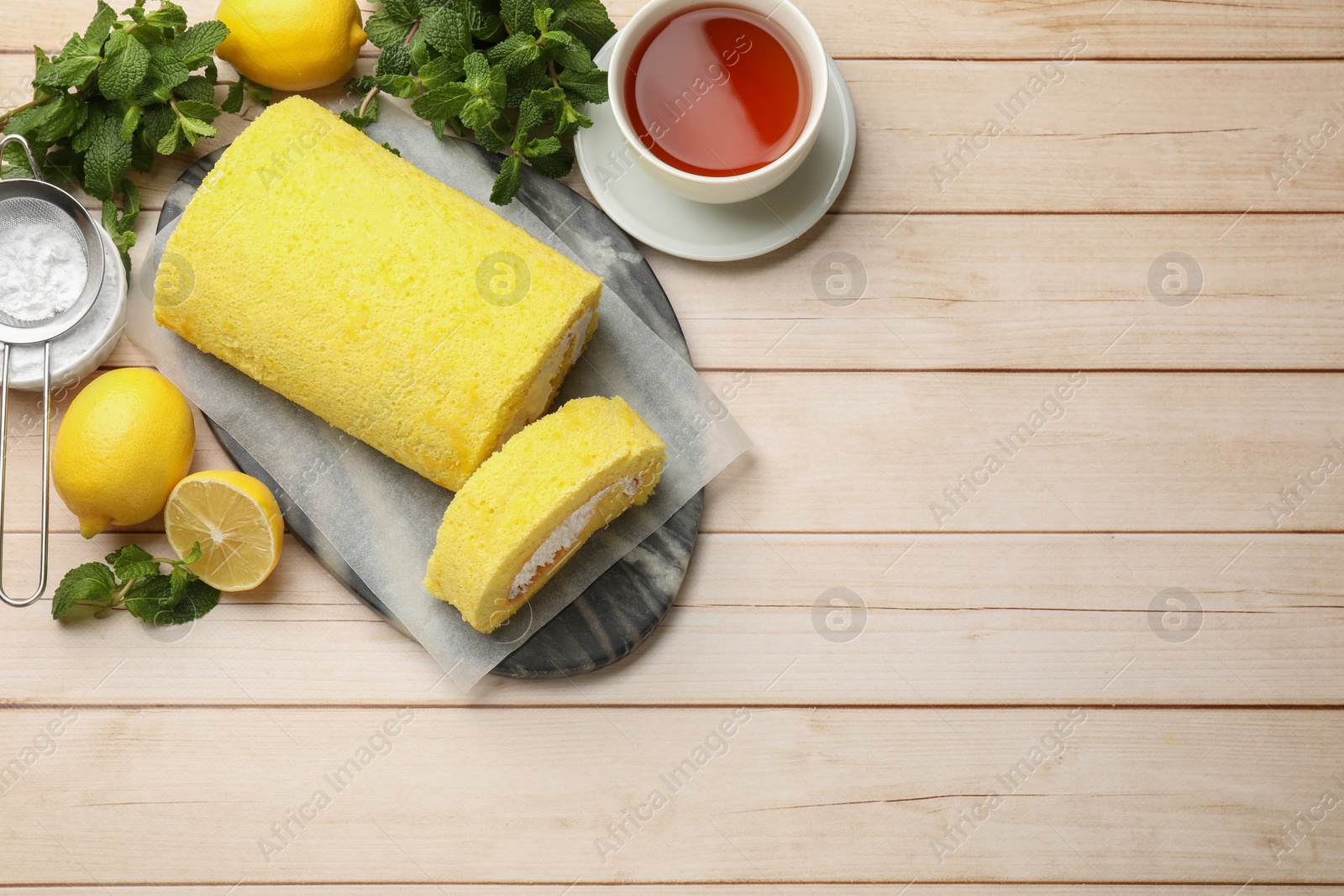 Photo of Delicious cake roll served on light wooden table, flat lay. Space for text