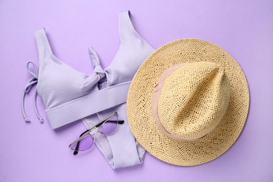 Stylish straw hat, bikini and sunglasses on violet background, flat lay