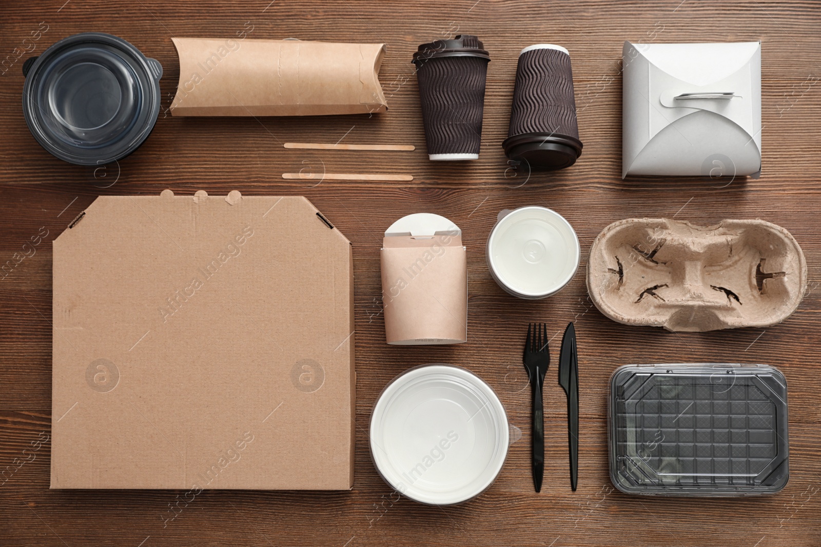 Photo of Flat lay composition with paper bags and different takeaway items on wooden background. Space for design