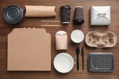 Flat lay composition with paper bags and different takeaway items on wooden background. Space for design