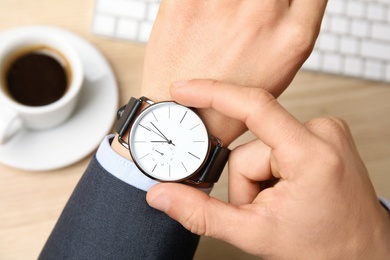 Photo of Businessman with wrist watch working at office table, closeup. Time management