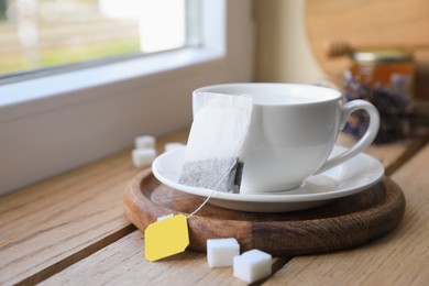 Photo of Tea bag and cup on wooden table indoors