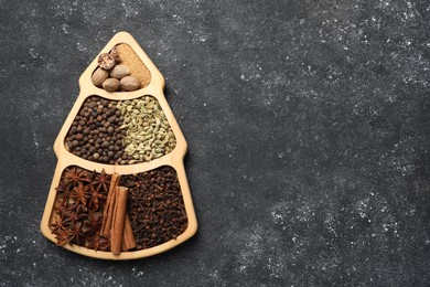 Photo of Different spices and nuts on dark gray textured table, top view. Space for text