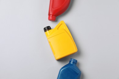 Photo of Motor oil in different canisters on light background, flat lay