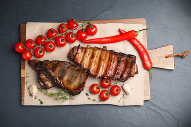 Tasty grilled ribs on black table, flat lay