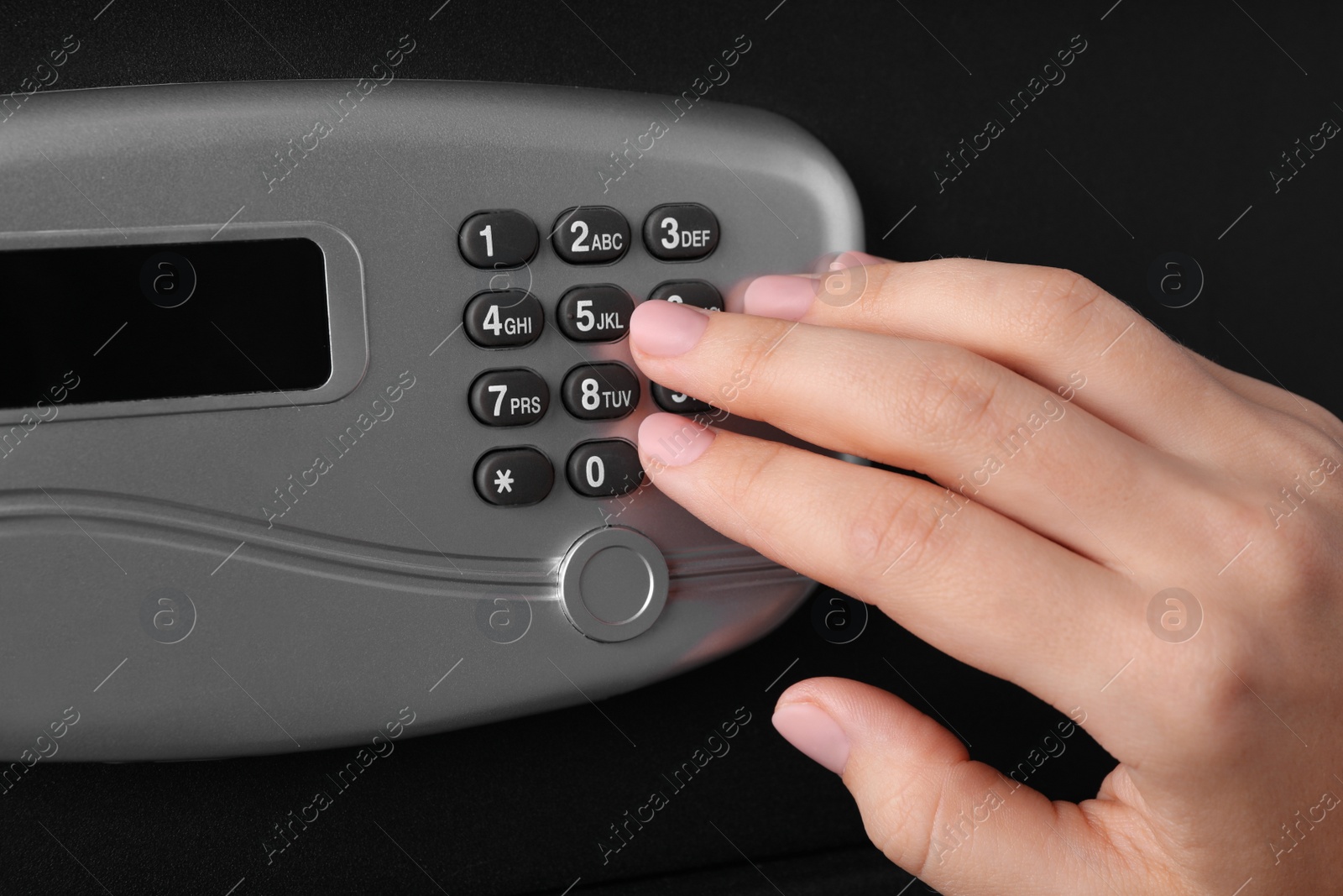 Photo of Woman opening black steel safe with electronic lock, closeup