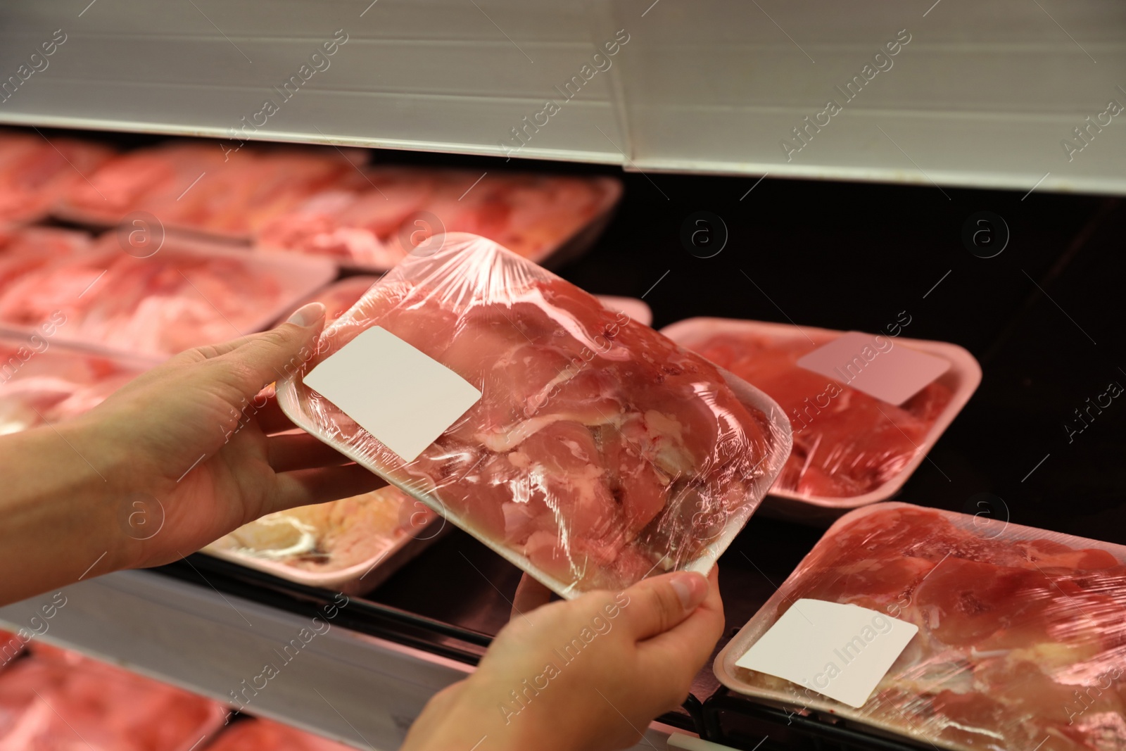 Photo of Woman choosing packed chicken meat in supermarket