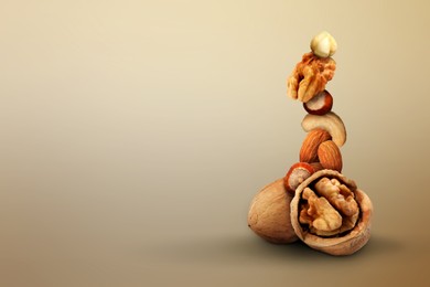 Image of Stacked different nuts on light brown gradient background, space for text