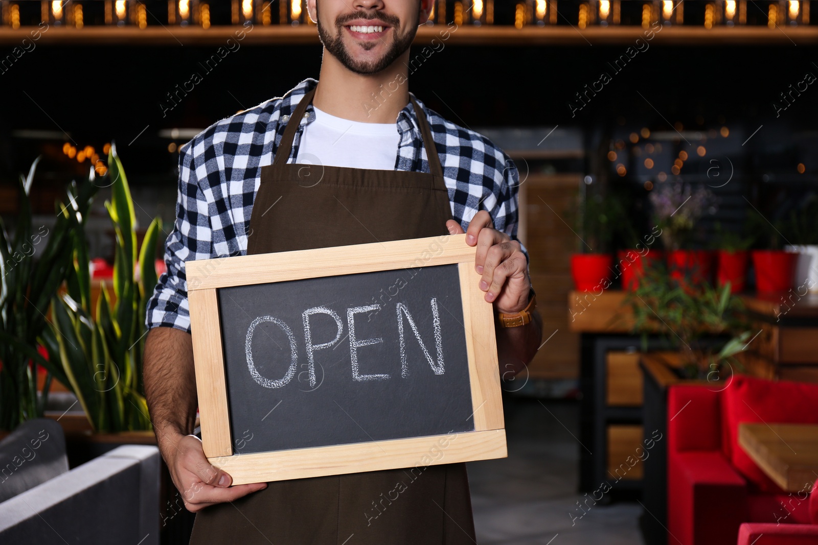 Photo of Young business owner holding sign OPEN in his cafe, closeup