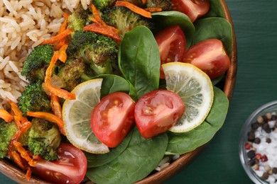 Tasty fried rice with vegetables on green wooden table, top view