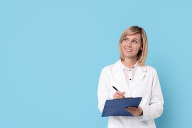 Smiling doctor with clipboard on light blue background. Space for text