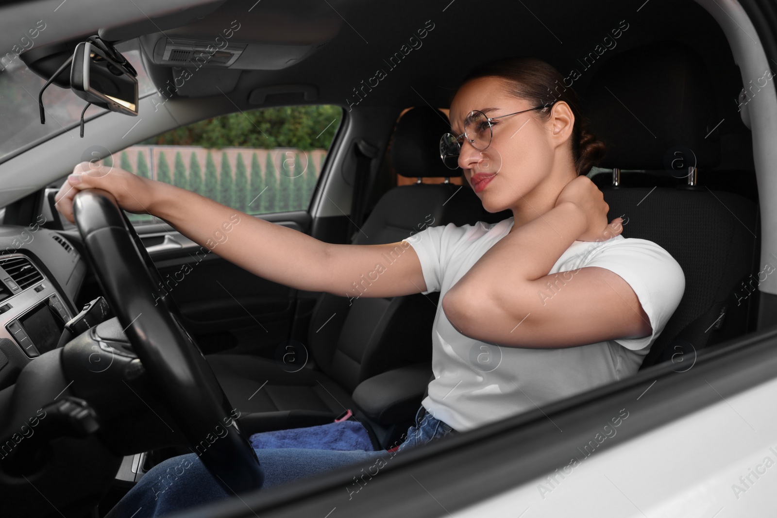 Photo of Young woman suffering from neck pain in her car