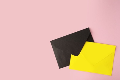 Colorful paper envelopes on pink background, top view. Space for text