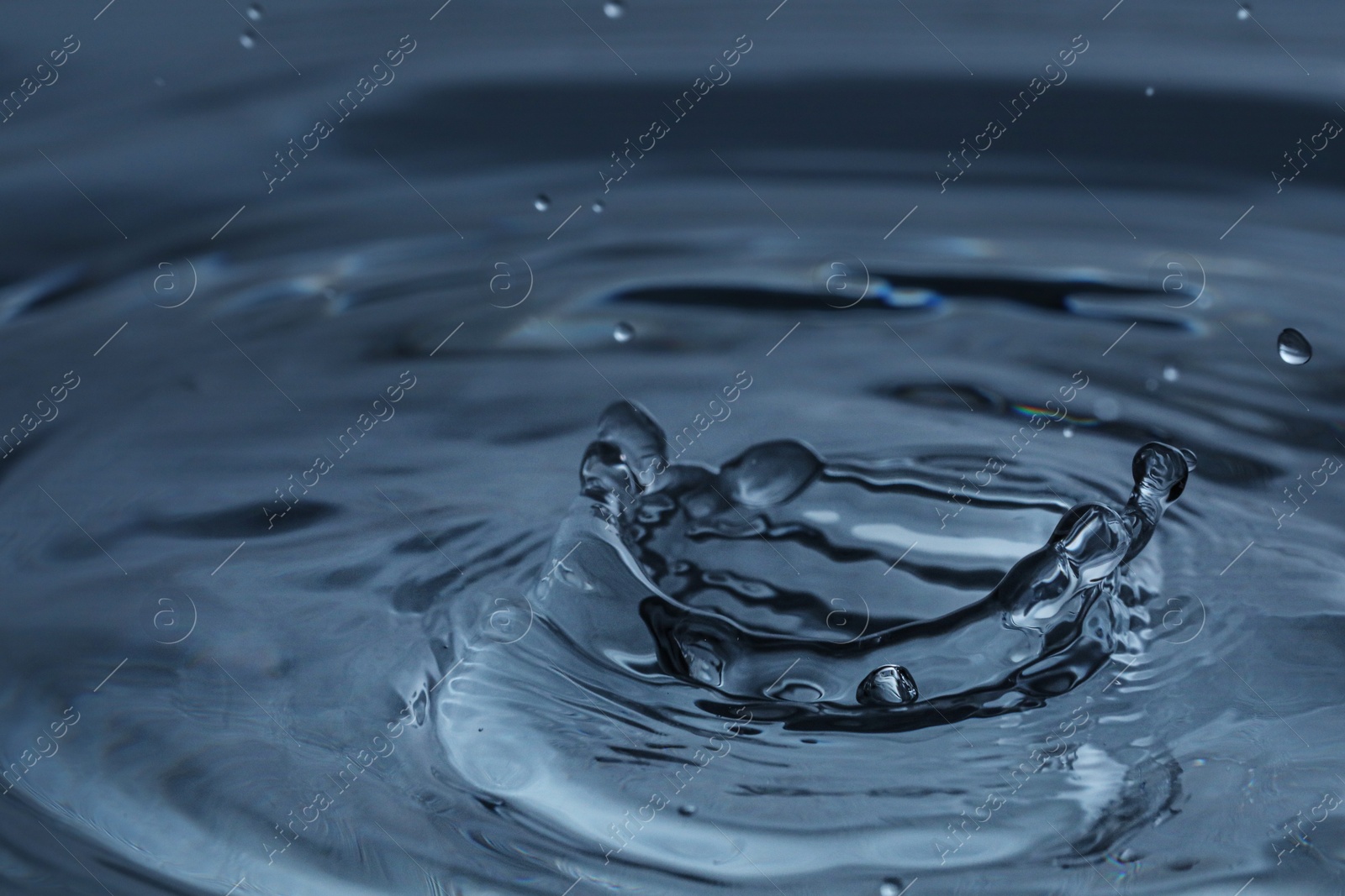 Photo of Splash of clear water with drops on dark blue background, closeup