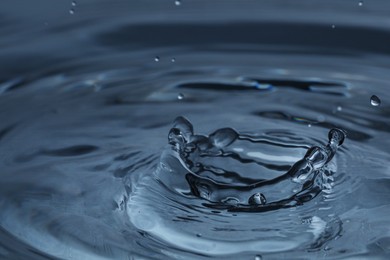 Splash of clear water with drops on dark blue background, closeup