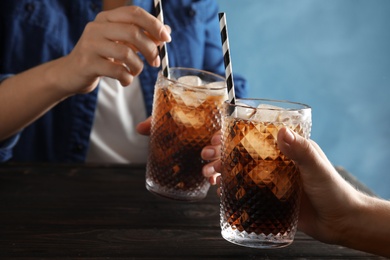 Friends with glasses of tasty refreshing cola at table, closeup view