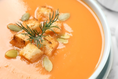 Photo of Tasty creamy pumpkin soup with croutons, seeds and dill in bowl, closeup