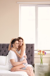 Photo of Happy young couple hugging on bed at home