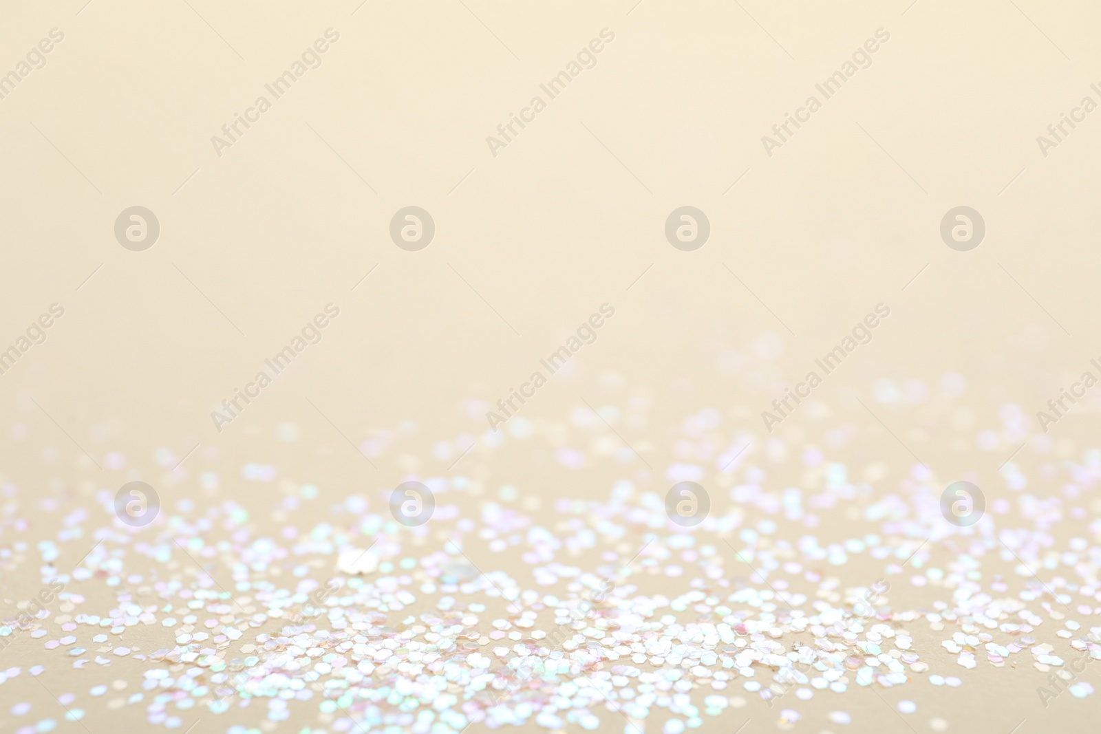 Photo of Shiny white glitter on beige background, space for text. Bokeh effect