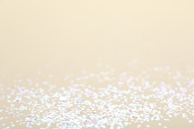 Photo of Shiny white glitter on beige background, space for text. Bokeh effect
