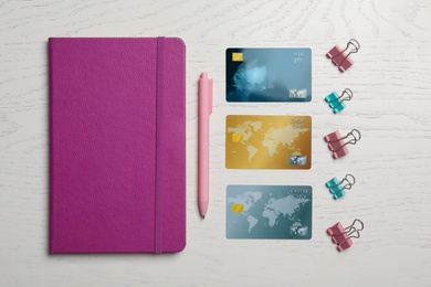 Flat lay composition with credit cards and stationery on white wooden background