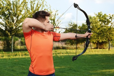 Man with bow and arrow practicing archery in park