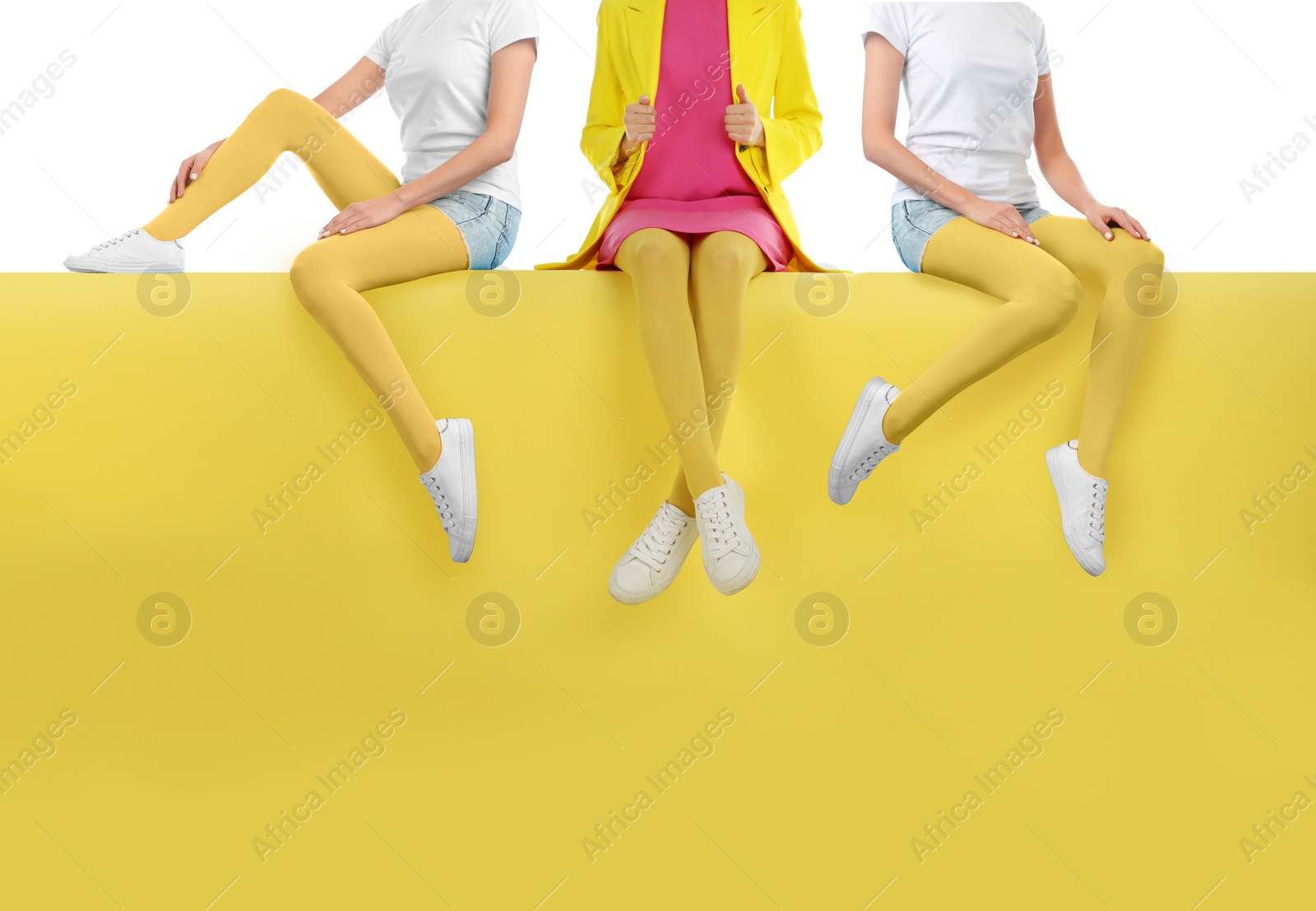 Image of Women wearing yellow tights and stylish shoes sitting on color background, closeup 