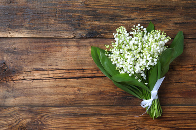 Beautiful lily of the valley flowers on wooden table, top view. Space for text