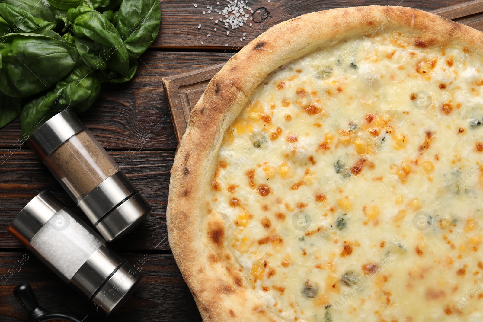 Photo of Delicious cheese pizza, basil and spices on wooden table, flat lay