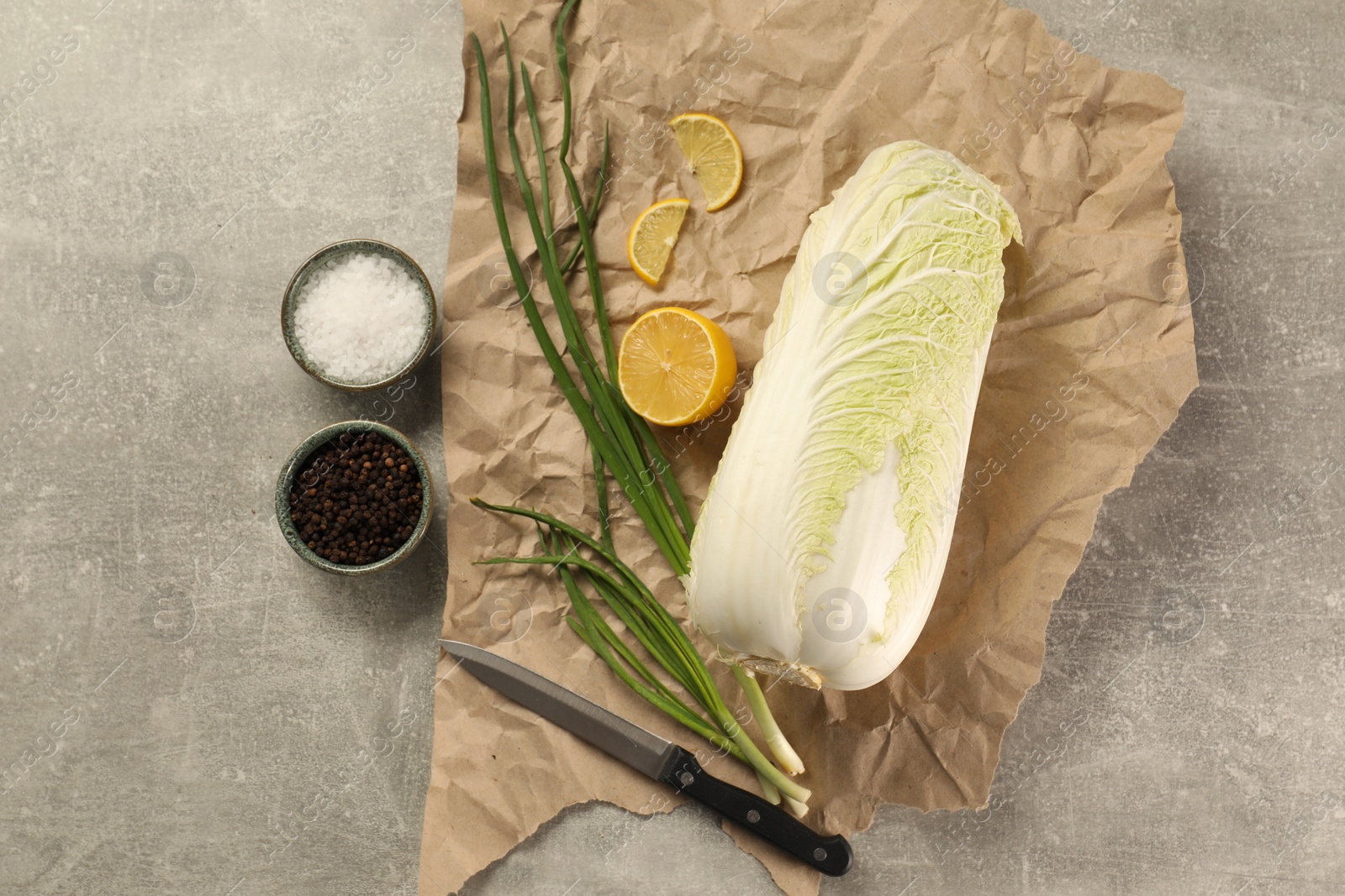 Photo of Fresh Chinese cabbage, lemon, green onion and spices on light grey table, flat lay