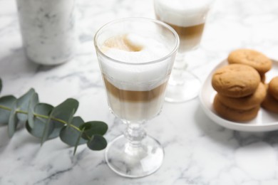 Photo of Delicious latte macchiato and tasty cookies on white marble table