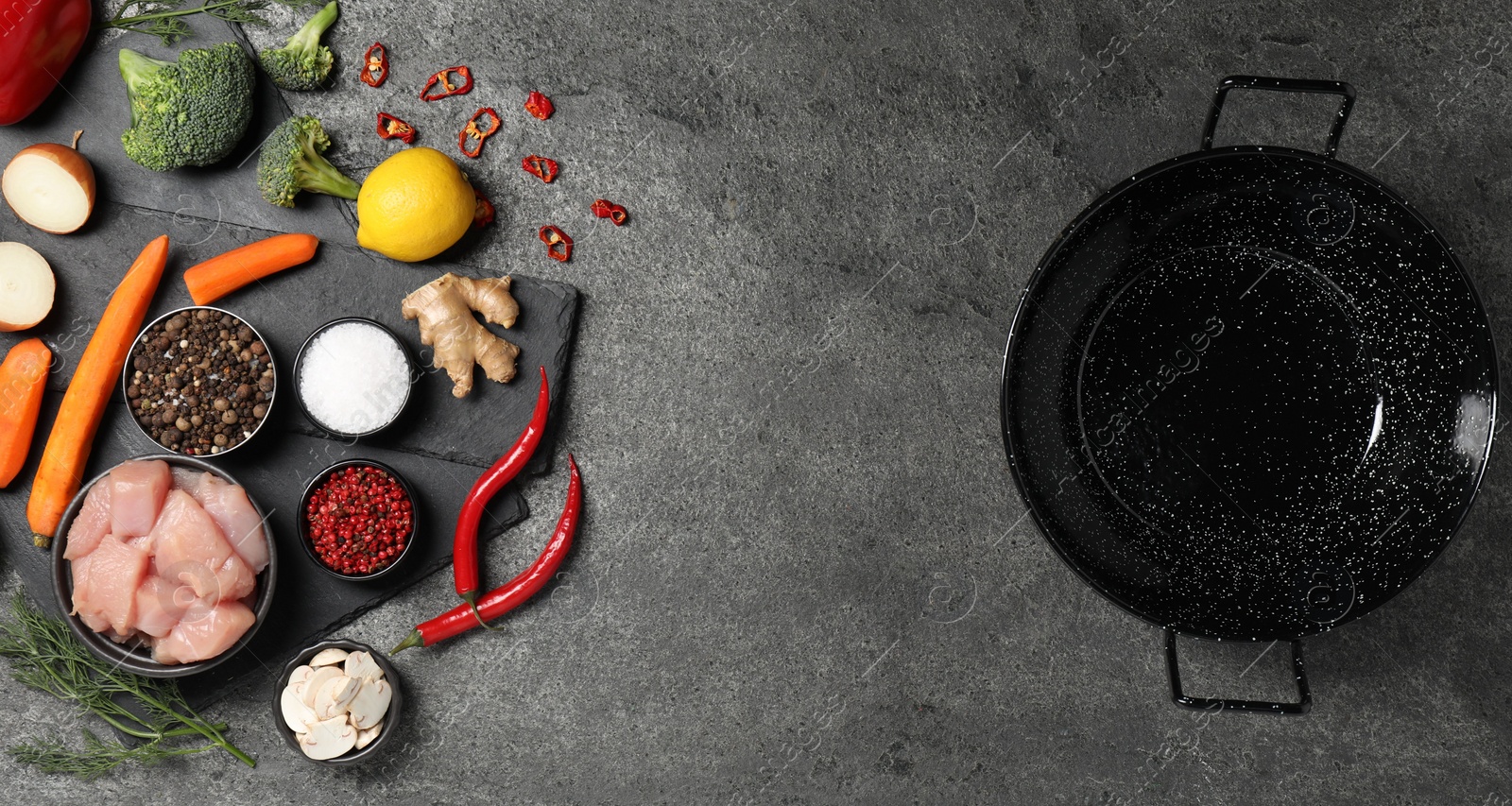 Photo of Empty iron wok and raw ingredients on grey table, flat lay. Space for text