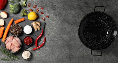 Photo of Empty iron wok and raw ingredients on grey table, flat lay. Space for text