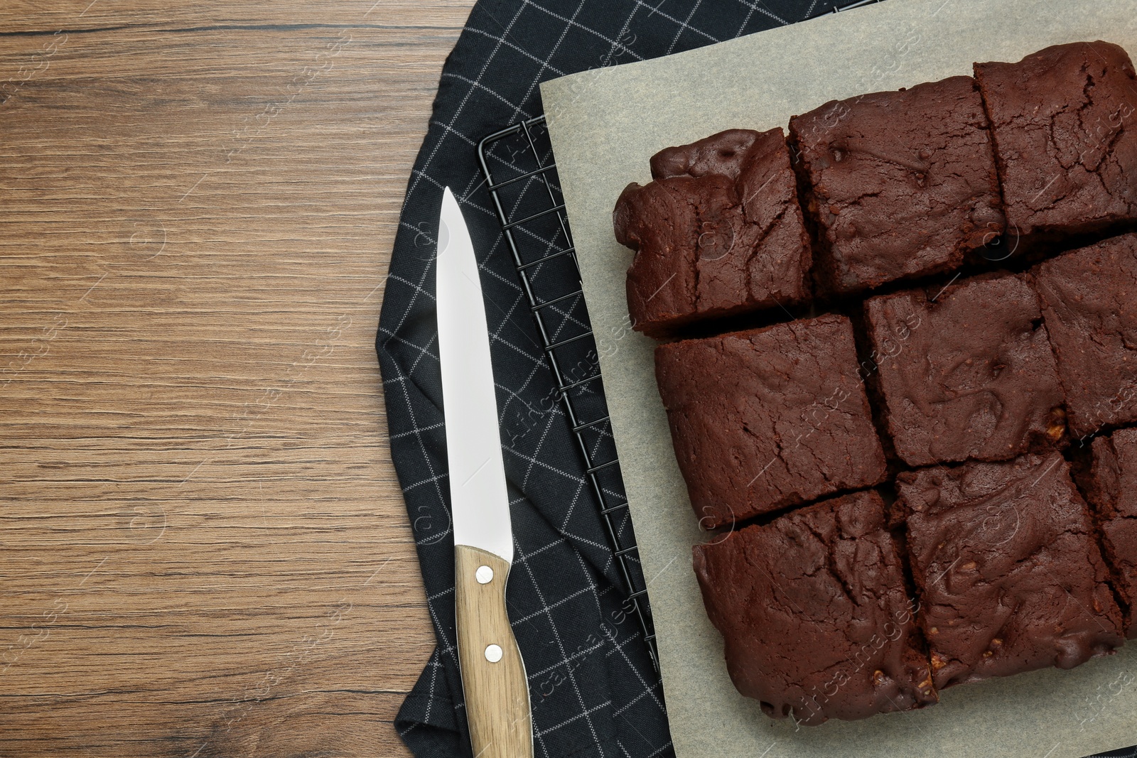 Photo of Delicious chocolate brownie cut in pieces on wooden table, top view. Space for text