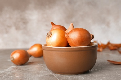 Bowl with fresh ripe onions on table