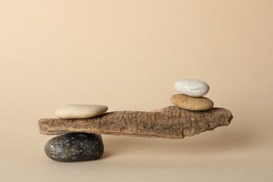 Photo of Tree branch with stones on beige background. Harmony and balance concept