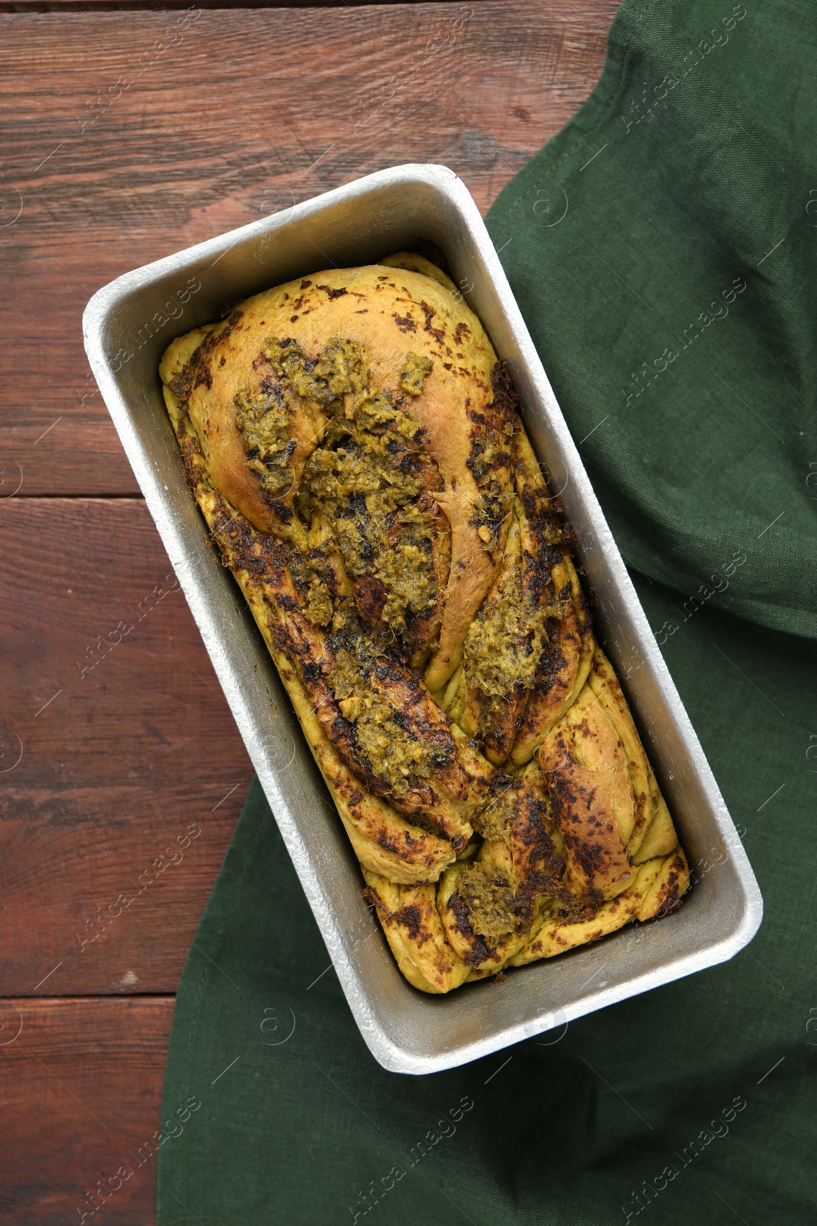 Photo of Freshly baked pesto bread in loaf pan on wooden table, top view