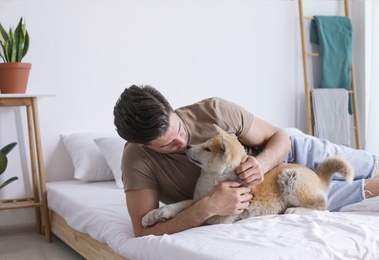 Happy man with his cute Akita Inu puppy at home