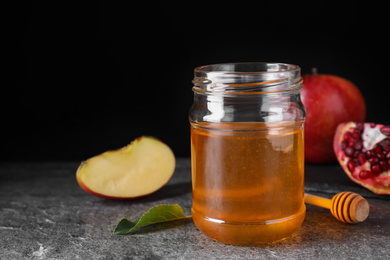 Photo of Honey near pomegranate and apple on grey table. Rosh Hashanah holiday