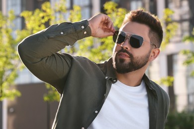 Handsome young man in sunglasses outdoors on sunny day